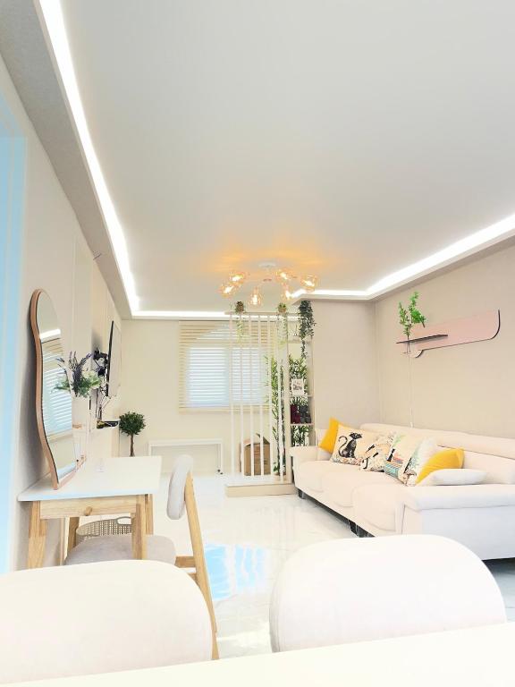 a living room with white furniture and a white ceiling at Maison Stay in Samgong