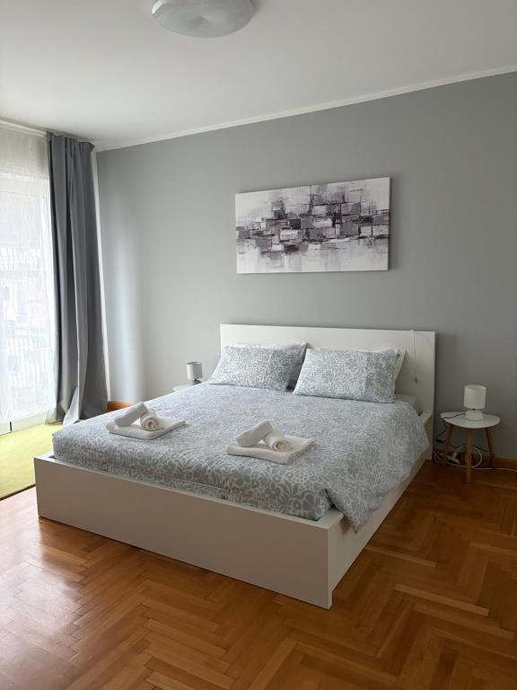 a white bedroom with a bed with two towels on it at La Maison V in Pontebba