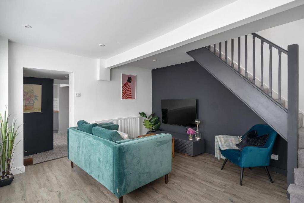 a living room with a blue couch and a staircase at Modern Cottage in Central Exeter in Dean