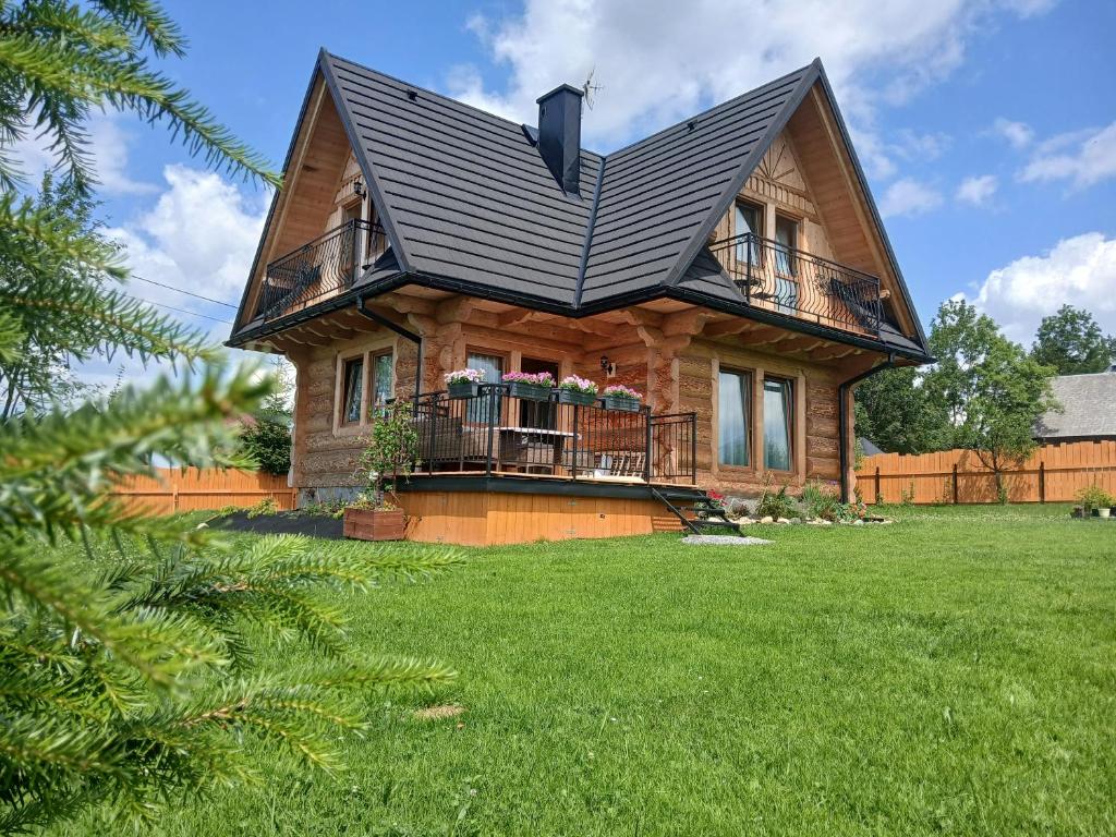 a house with a black roof and a green yard at Tatra West Farm in Dzianisz