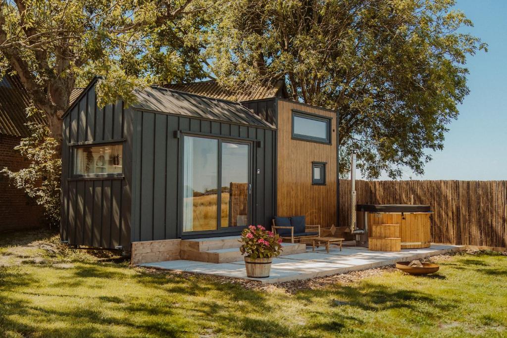 a black tiny house with a patio in a yard at Tiny Bali spa house in Menaldum