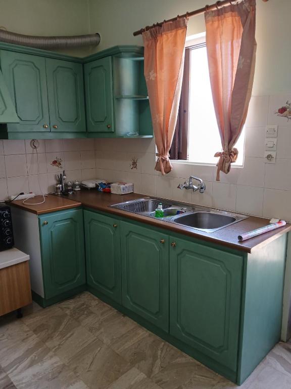 a green kitchen with a sink and a window at Livanos Apartments in Neapoli Voion