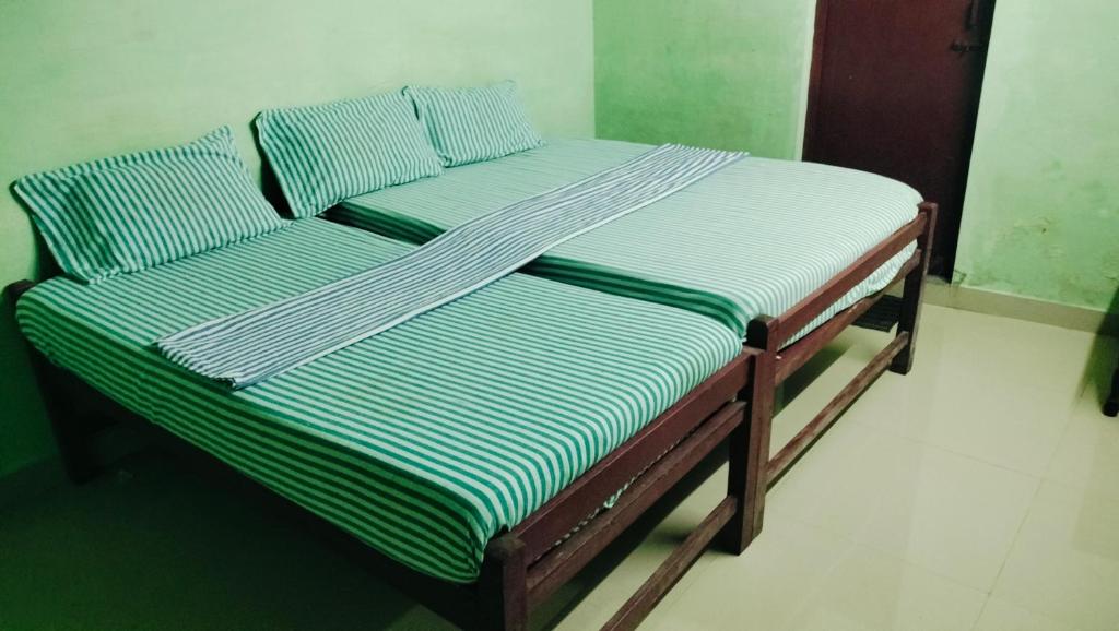 a bed with green and white striped sheets and pillows at SMK cottage in Rāmeswaram