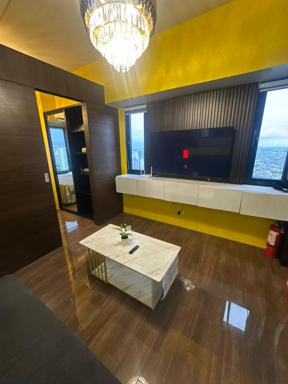 a living room with a table and a television at Sunbeam - Lush Residence in Manila