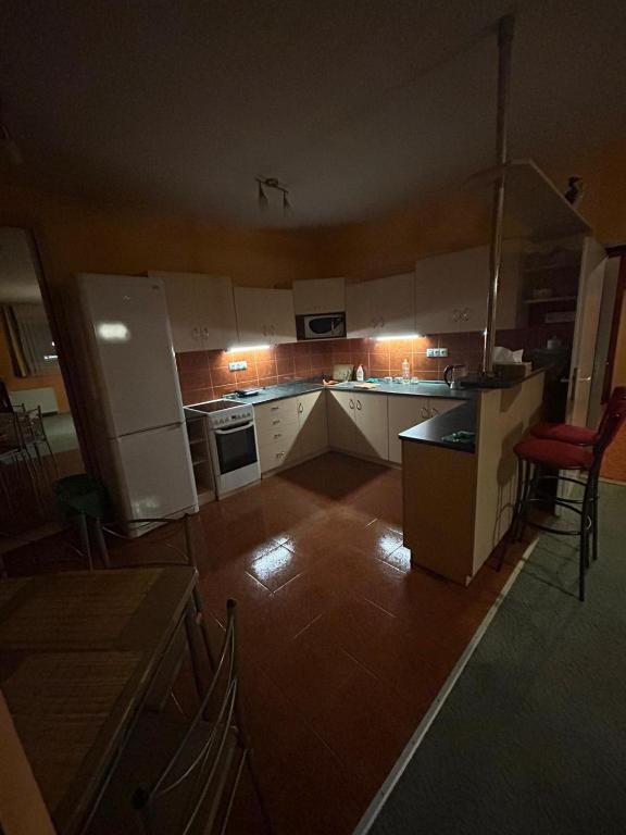 a large kitchen with white appliances and red chairs at Apartmán u Milana v Pisku in Písek