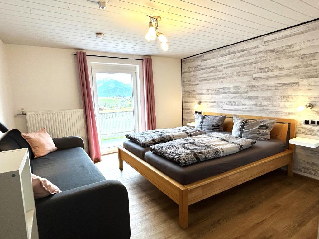 a bedroom with a bed and a couch at FeWo Beim Huber in Hopferau