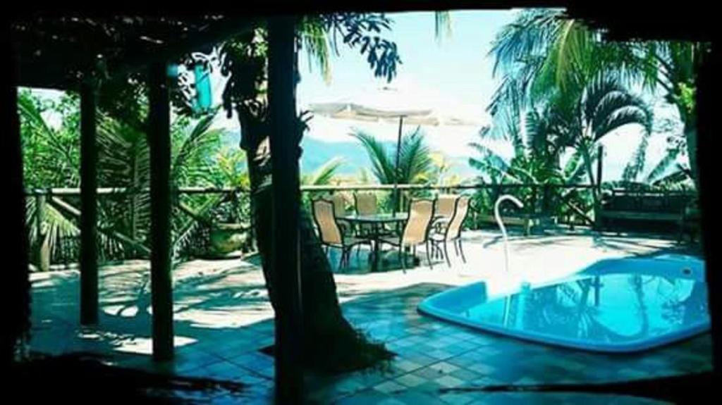 d'une baignoire installée sur une terrasse avec une table et des chaises. dans l'établissement Suites Canto dos Passaros, à Ilhabela