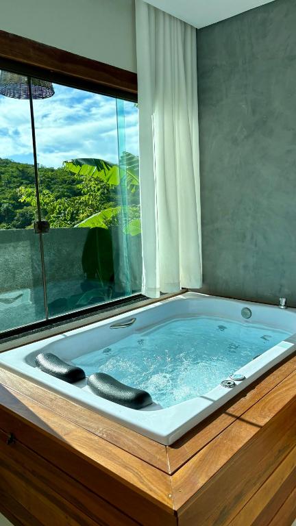 a jacuzzi tub in a room with a window at Cipó Lofts - 3 lofts incríveis na Serra do Cipó in Santana do Riacho