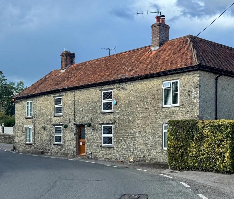 a brick house with a red roof on a street at Arcadia Cottage, Mere in Mere