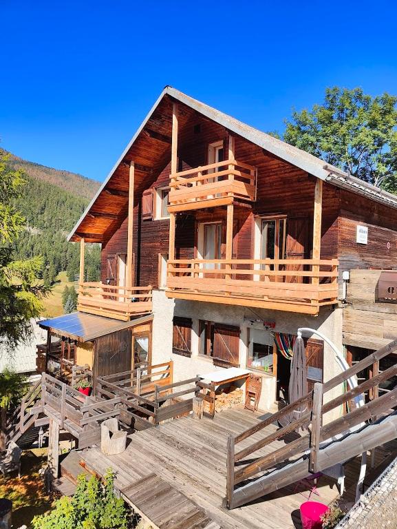 a large wooden house with a large deck at Chambre d'hôtes Chalet AILLEURS in Molines-en-Queyras