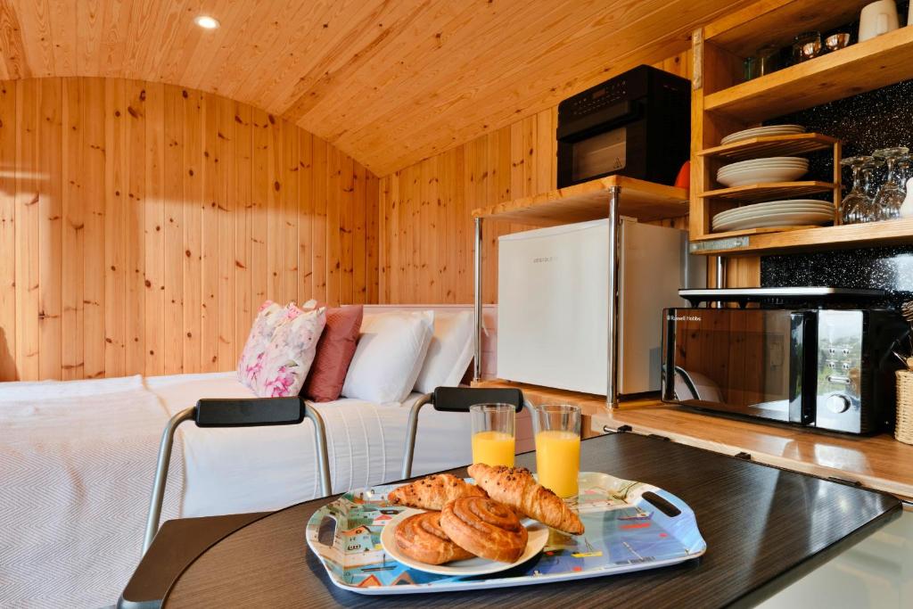 a room with a table with a tray of bread at Finest Retreats - Demelza Shepherds Hut in Grade