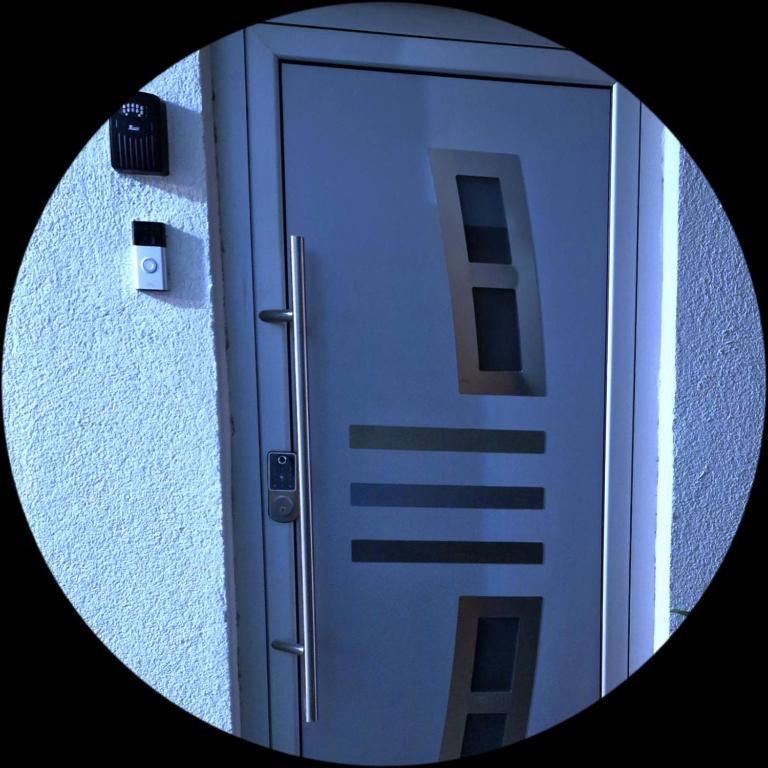 a round mirror reflecting a door with a building at Apartment Sekulic in Doboj