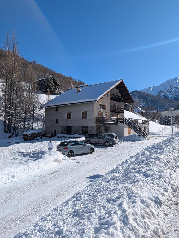 a house with two cars parked in the snow at Ailleurs La Chalp à Saint-Véran in Saint-Véran