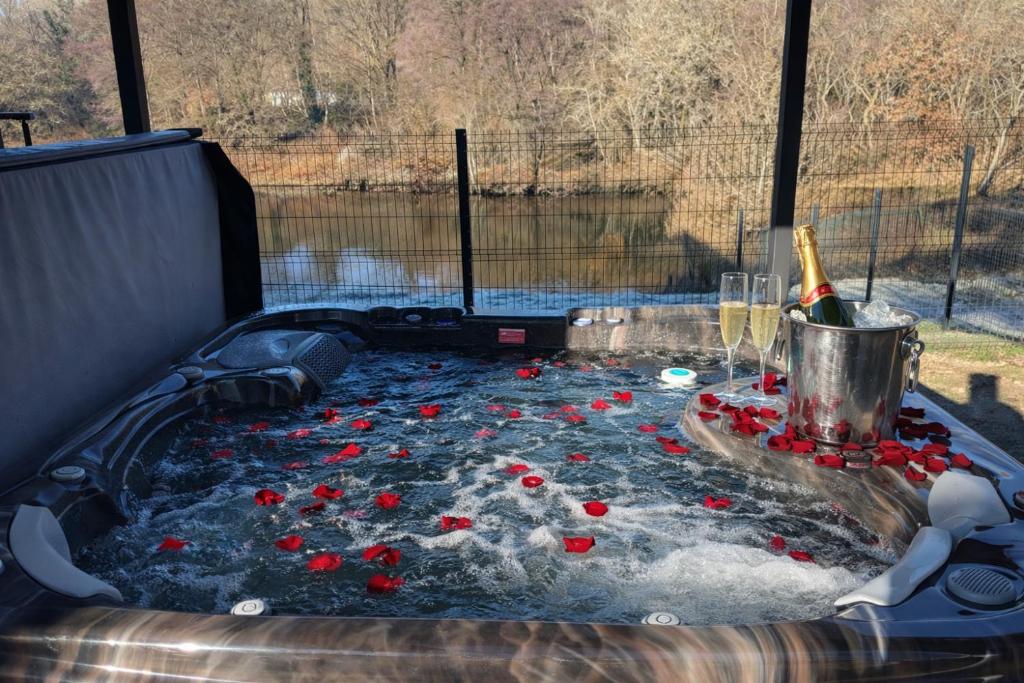 a hot tub filled with red roses and champagne at Studio avec spa vue Moselle in Dinozé