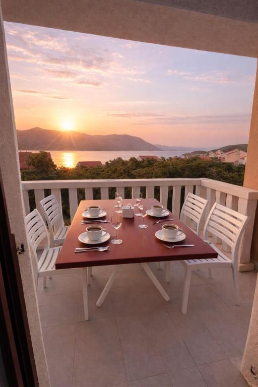 a table on a balcony with a view of the sunset at Apartments Oxygen in Račišće