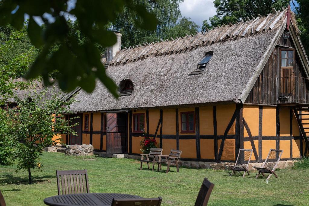 a house with a thatched roof and chairs in the yard at Alunbruket B & B in Brösarp