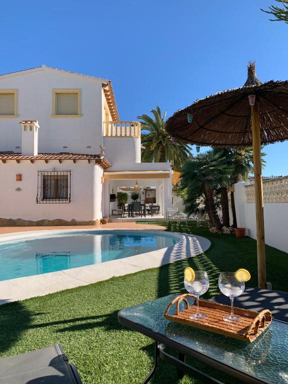 a house with a swimming pool and a table with wine glasses at Casa Laura by Sun & Sea Homes in Moraira