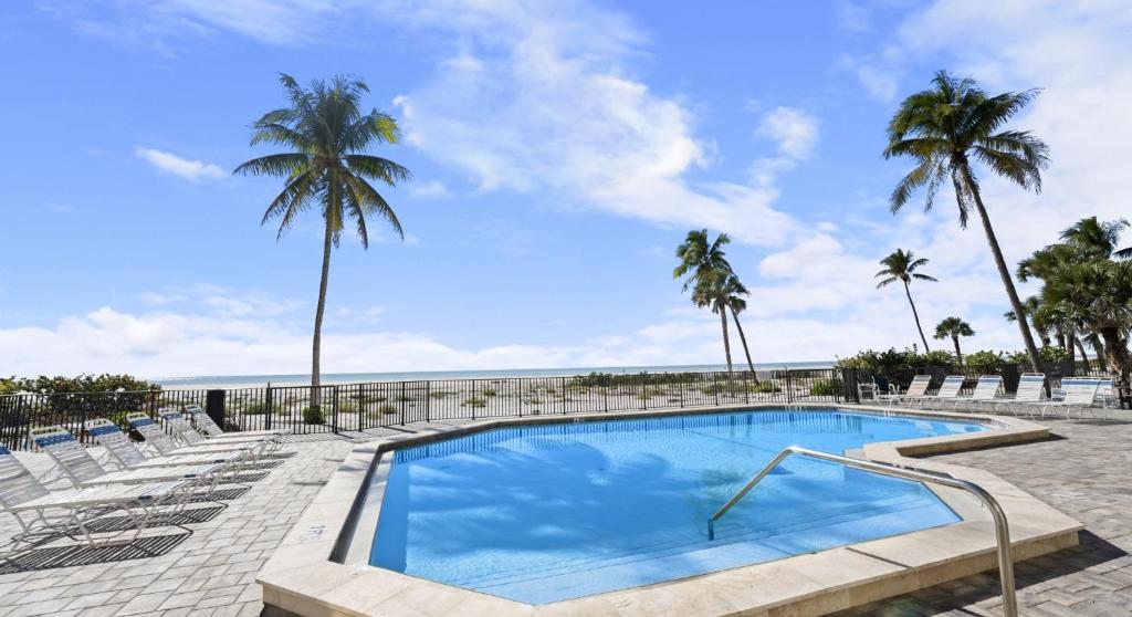 a swimming pool with chairs and palm trees at Mariner's Boathouse and Beach Resort by CoolVacay in Fort Myers Beach