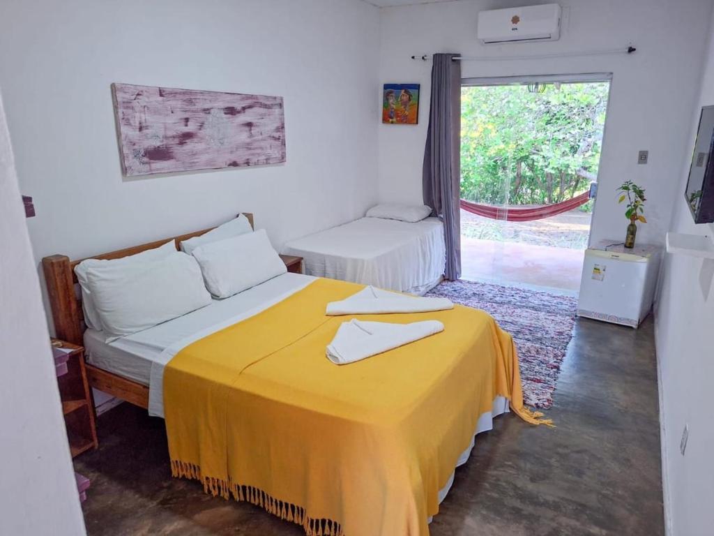 a bedroom with a bed with a yellow blanket at Pousada dos Mundos1 in Conde