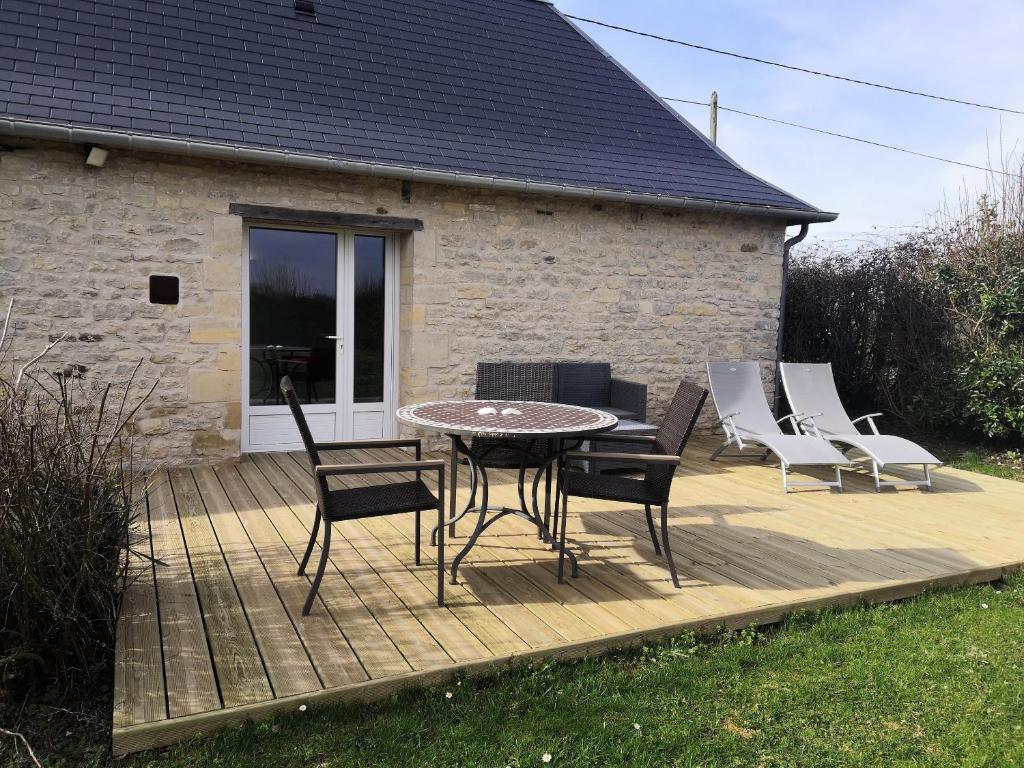 a wooden deck with a table and chairs on it at Gîte La Buhennerie 2 personnes in Longues-sur-Mer