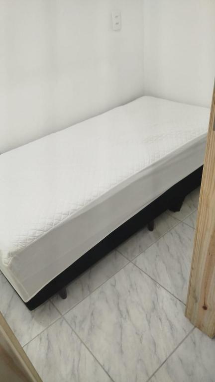 a bed frame with a white mattress on the floor at Republica Fusinato in Itajaí