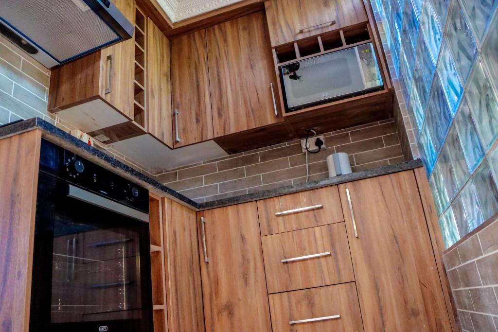 a small kitchen with wooden cabinets and a microwave at GT holiday home in Chobe