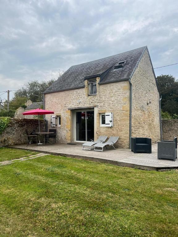 a brick building with a patio and a red umbrella at Gîte Le Val de Marigny 2 personnes in Longues-sur-Mer
