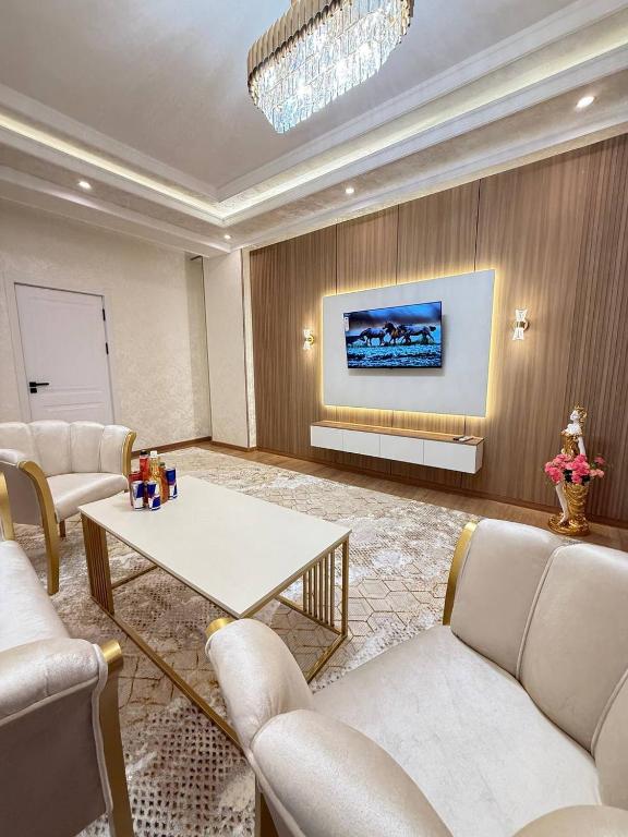 a living room with couches and a table and a tv at Silk Road Retreat City Center in Bukhara