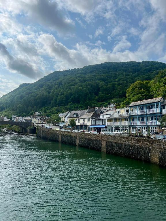 a river with houses and a town next to a mountain at Riverside Cottage B&B in Lynmouth