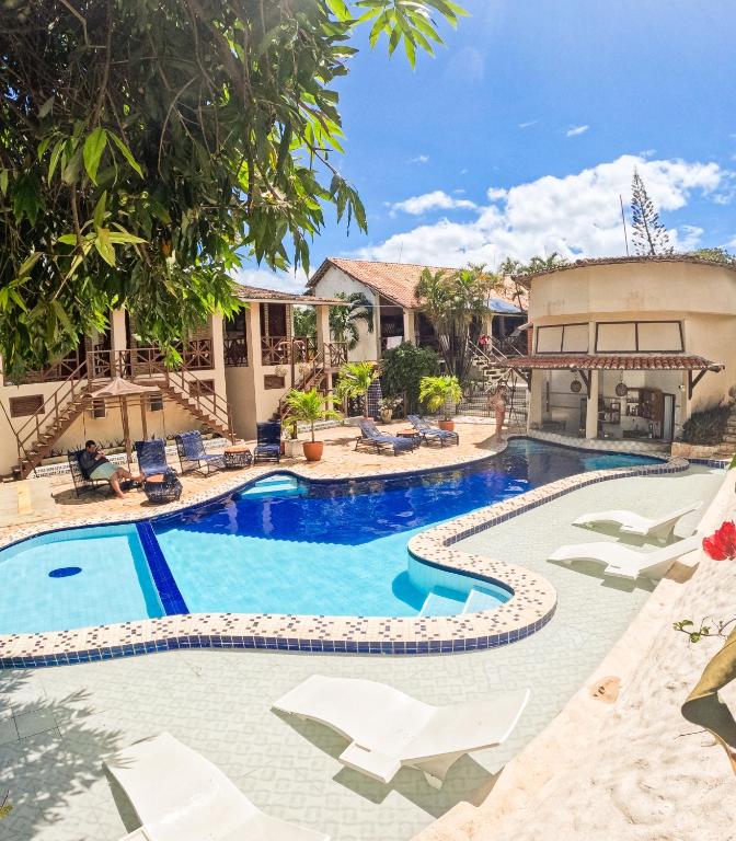a pool at a resort with chairs and trees at Pousada Bicho Preguiça in Pipa