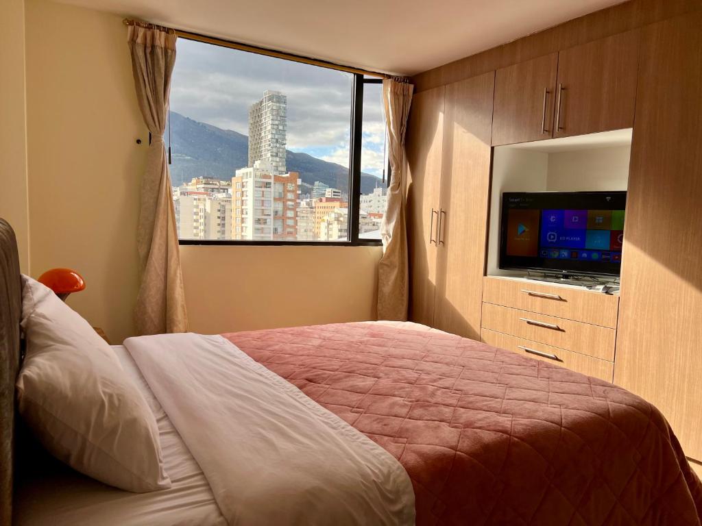 a bedroom with a bed and a large window at Amplia suite cerca a La Carolina - Av 6 Diciembre in Quito