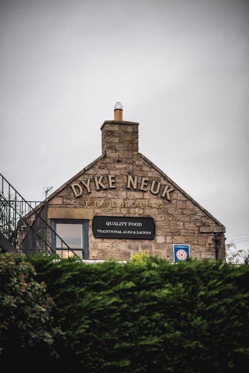 a building with a sign on the side of it at Dykeneuk rooms in Hartburn