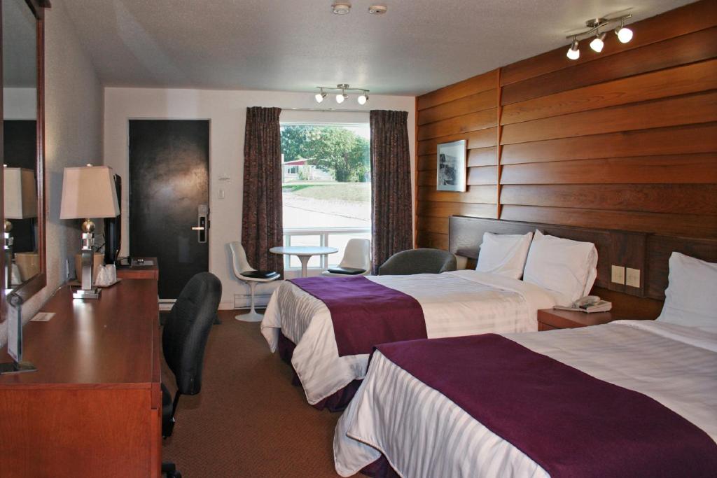 a hotel room with two beds and a table at Motel à la Brunante Petit Déjeuner inclus avec la chambre in Sainte-Anne-des-Monts
