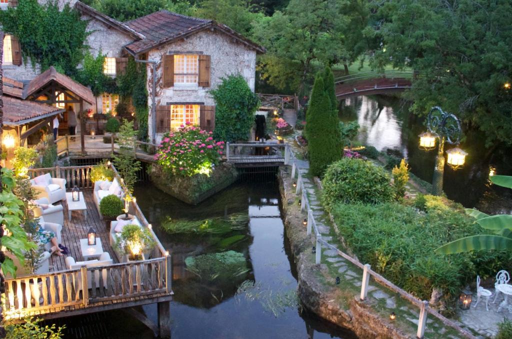 une maison avec un pont sur une rivière dans l'établissement Le Moulin du Roc, à Brantôme