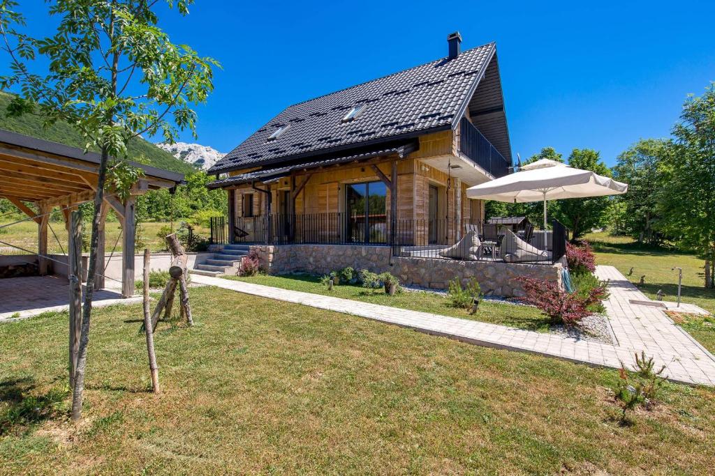 a wooden house with an umbrella in the yard at Modern Alpine Monsalbius Chalet in Baške Oštarije