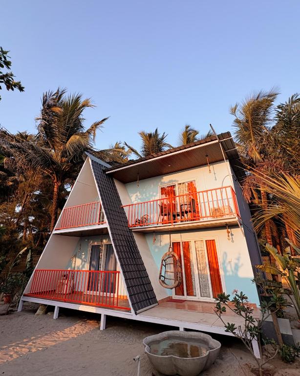 a house with balconies and trees in the background at Kieh Beachfront Villa in Mandrem