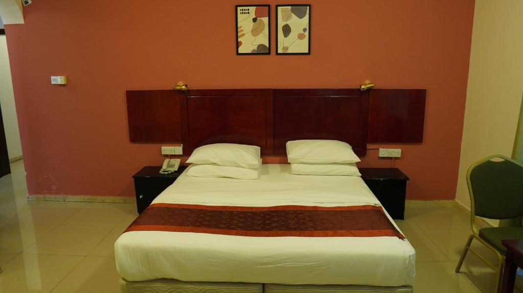 a bedroom with a large bed with a red wall at Hotel Summersands Al Wadi Al kabir in Muscat