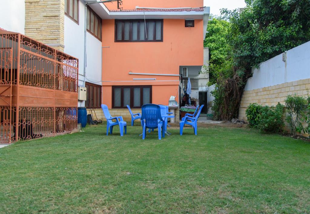 a patio with blue chairs and a table in a yard at Patel Residency Guest House in Karachi