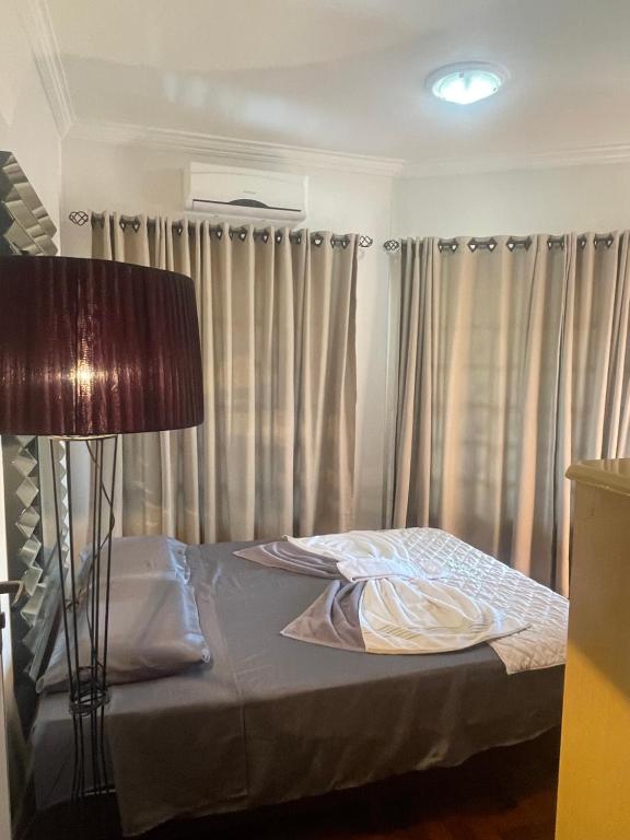 a bed in a room with curtains and a lamp at Equilíbrium Quarto de casal com banheiro compartilhado in Marechal Cândido Rondon
