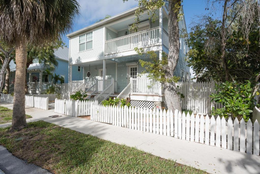 a white picket fence in front of a white house at ISLAND TIME ON THE GREEN in Key West