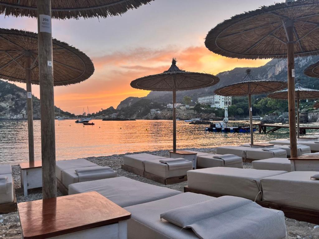 a group of lounge chairs and umbrellas on a beach at Poseidon Beach Bar & Restaurant Apartments in Paleokastritsa