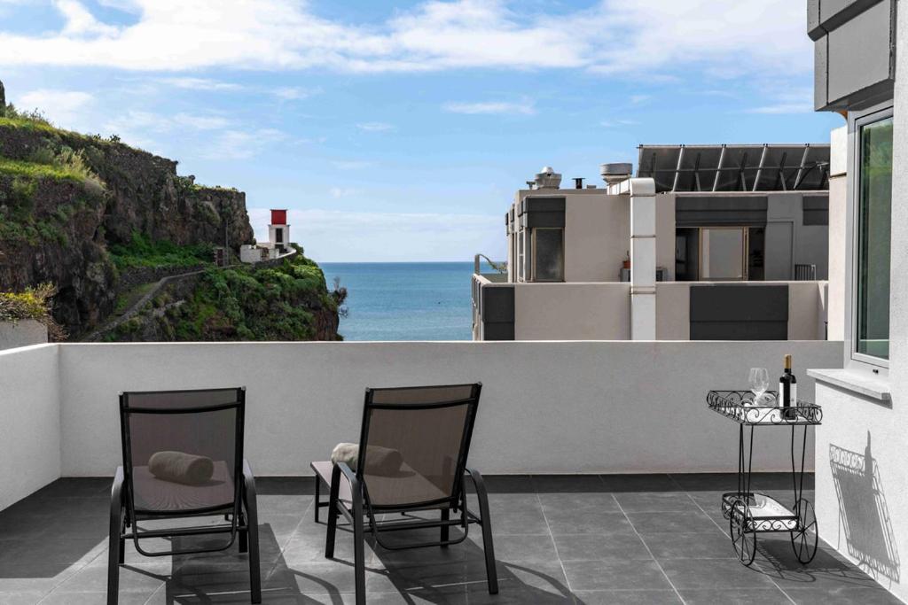 a balcony with two chairs and a view of the ocean at OurMadeira - Terrace Sea Apartments in Ribeira Brava