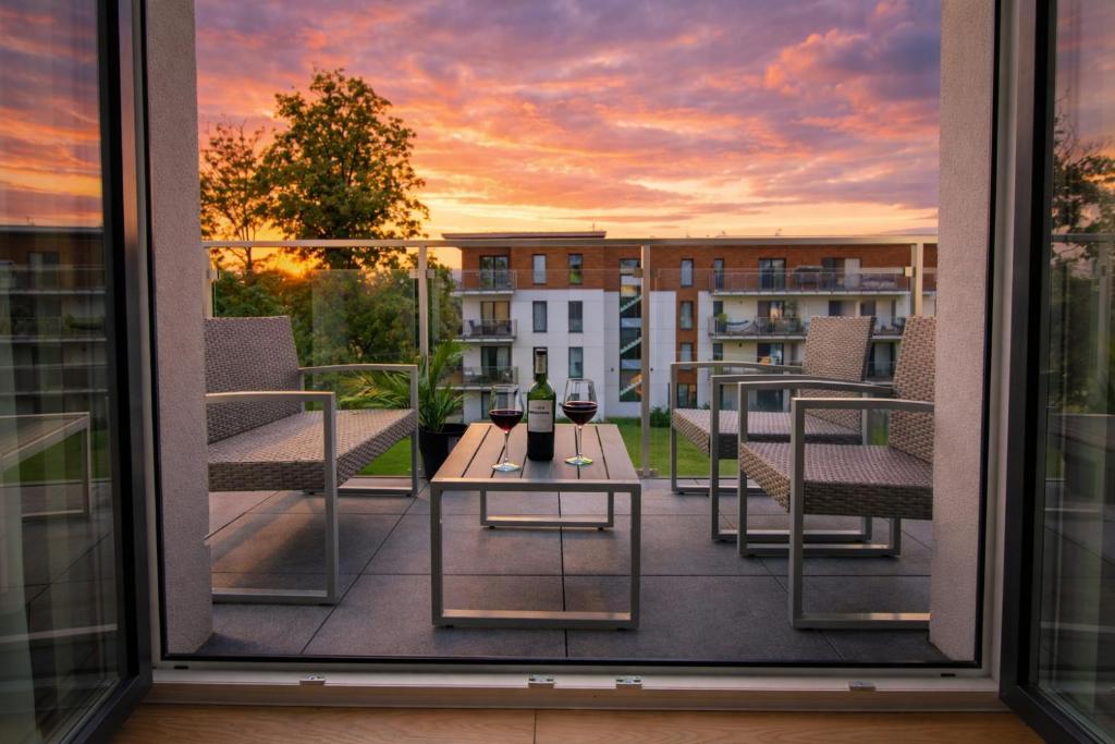 a balcony with a table with a bottle of wine at Marina Nautica - nowy, parking podziemny, winda, Netflix i Max, TV55" in Iława