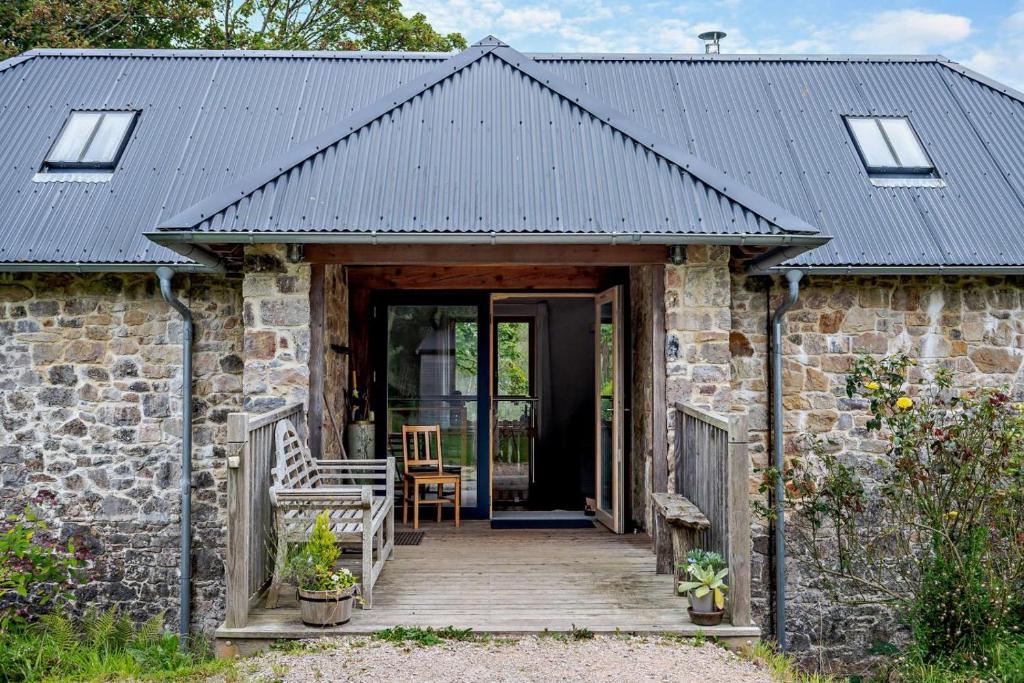 a stone house with a black roof and a wooden porch at 3 Bed in Dartington oc-b30033 in Darlington