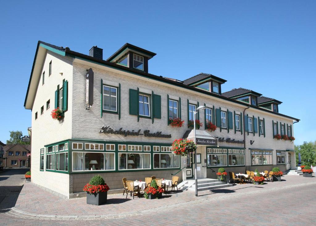 un grand bâtiment avec des tables et des chaises devant lui dans l'établissement Hotel Kirchspiels Gasthaus, à Nortorf