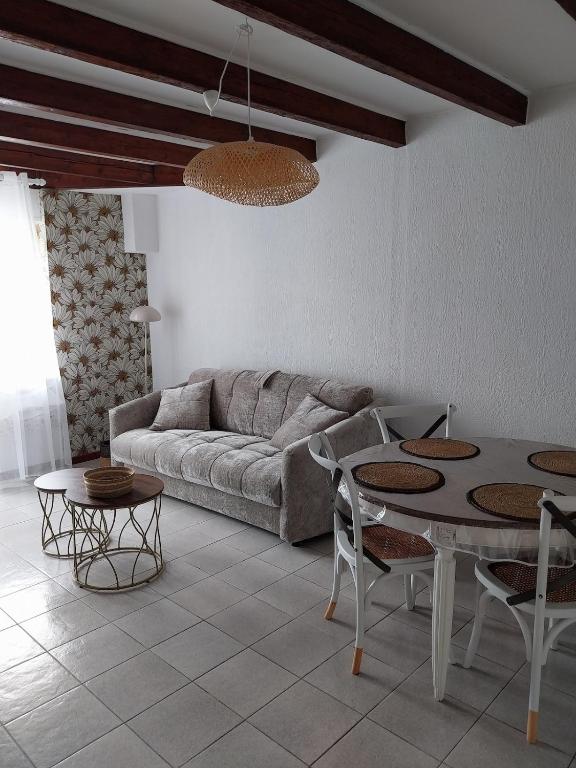 a living room with a couch and a table and chairs at Maisonette Syl' -vie in Cognac