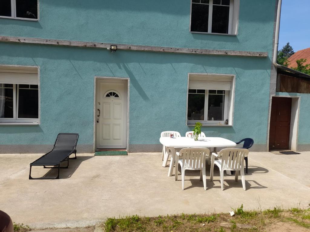 a table and chairs in front of a blue building at Chambre d'hôtes dans un écrin de verdure in Dambach