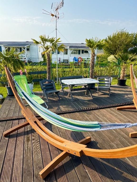 a hammock and a table and chairs on a deck at Domki GAMA in Gąski