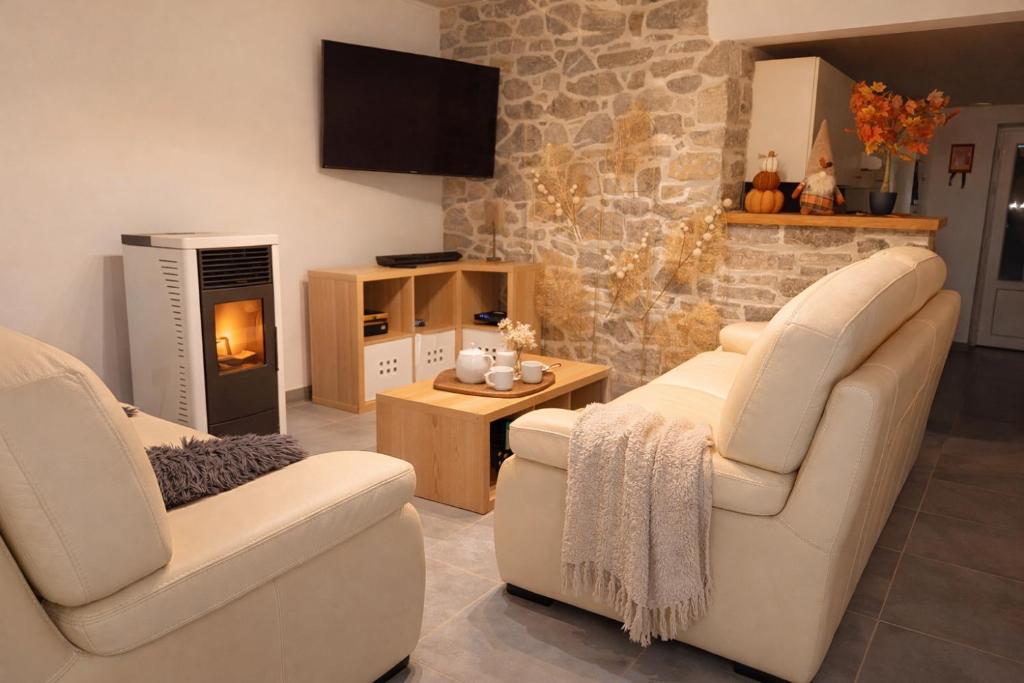 a living room with two chairs and a fireplace at Au Chant des Roches Gîte en pierre avec jardin à Cerfontaine in Cerfontaine