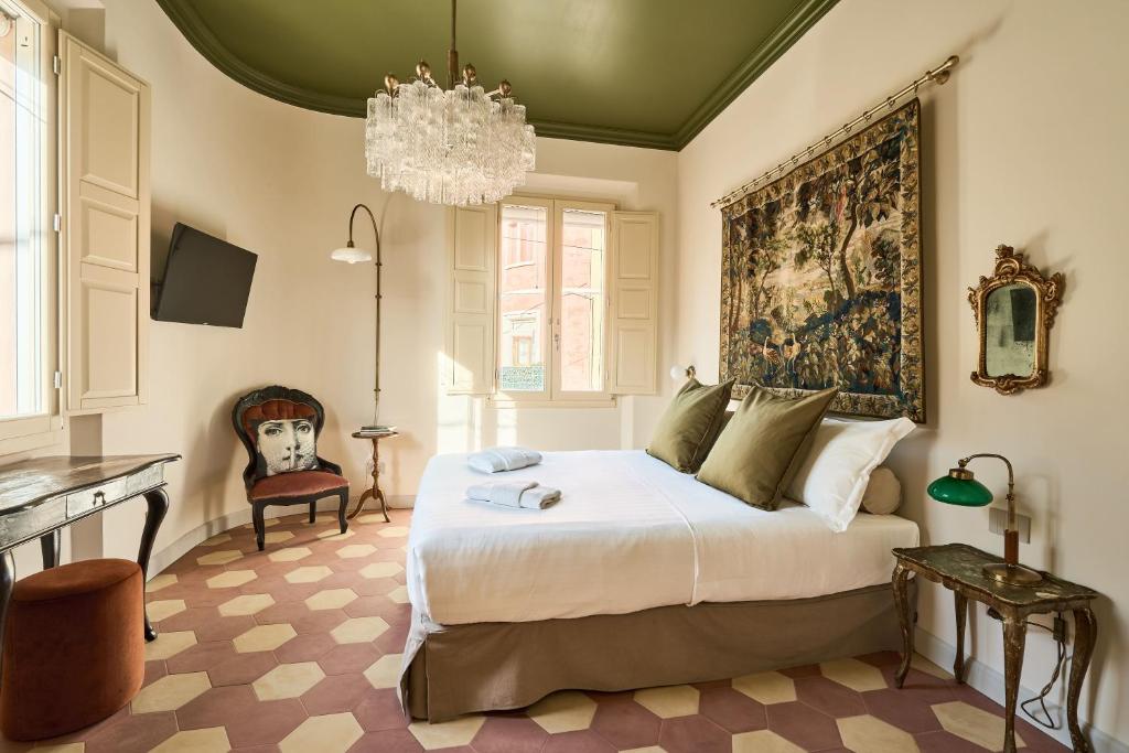 a bedroom with a large bed and a chandelier at Boutique Apartment nel Borgo - Casa Olga e Casa Ilde - Le Dimore del centro in Santarcangelo di Romagna